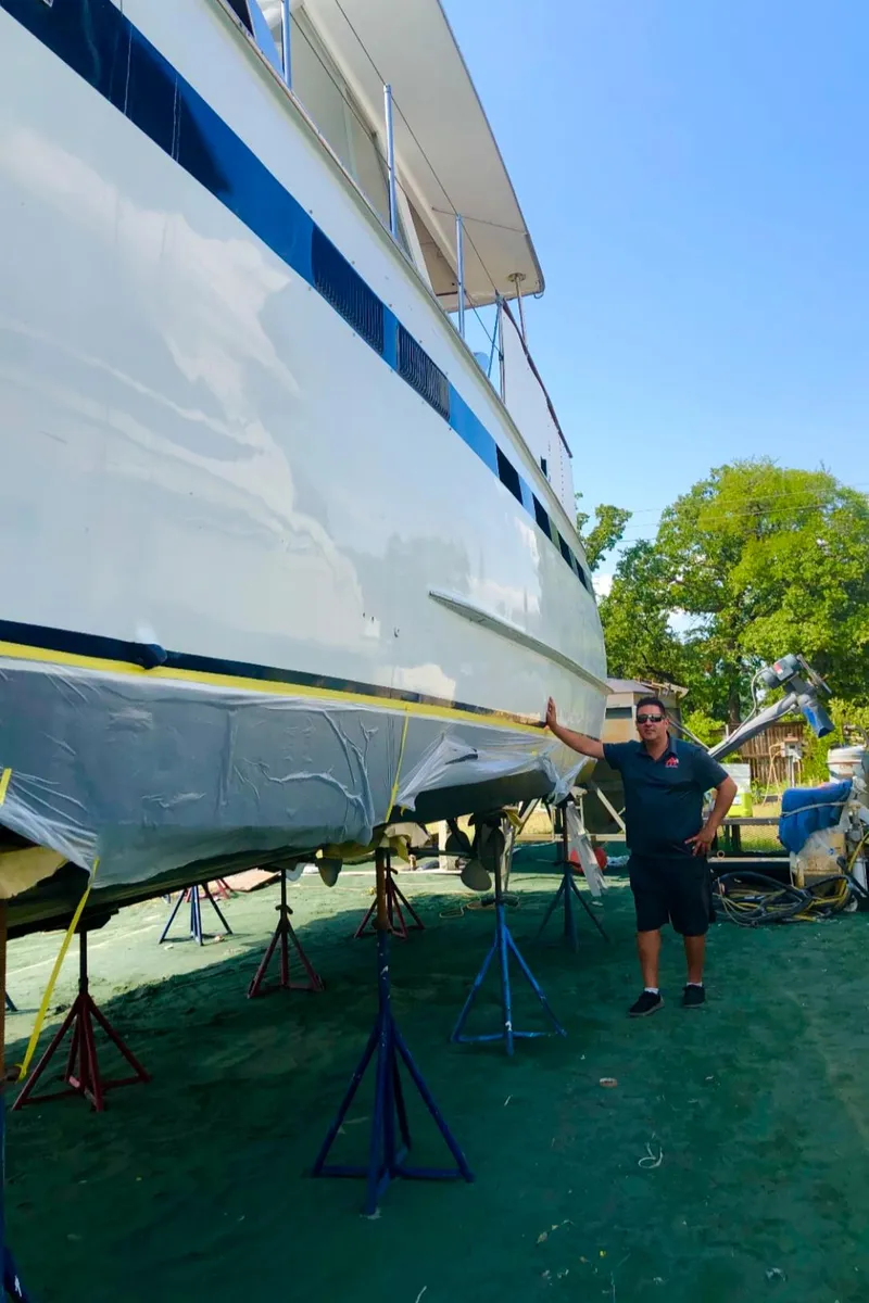 Slide: The Image of Man standing next to a 1969 Chris-Craft 46 Roamer yacht on dry dock. - 31