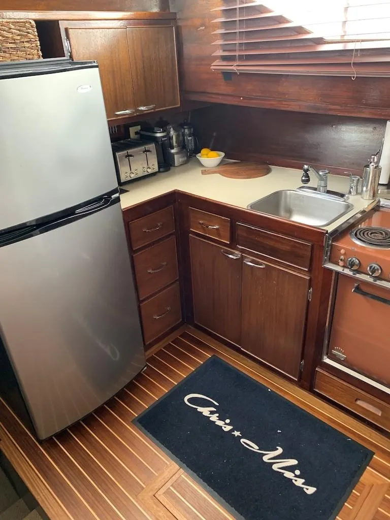 Slide: The Image of 1969 Chris-Craft 46 Roamer kitchen with stainless steel fridge and wooden cabinetry. - 8