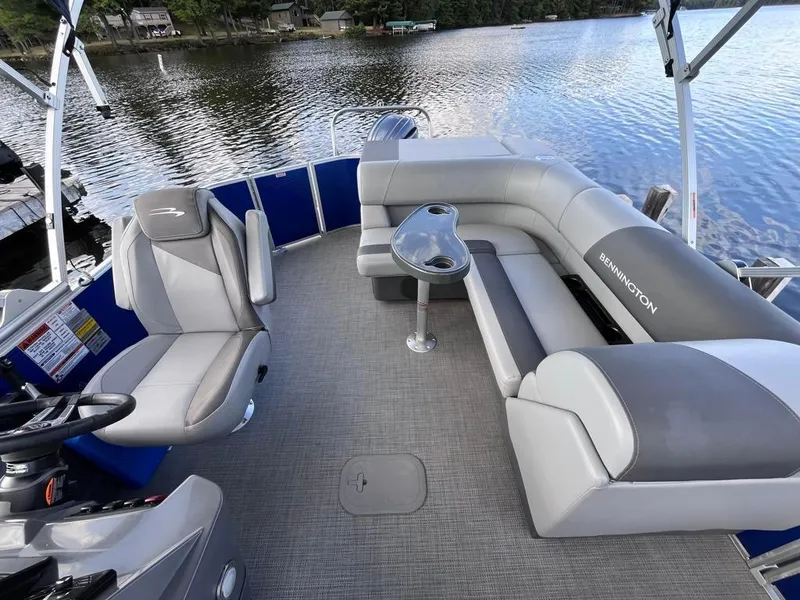 Slide: The Image of 2024 Bennington 22SVL-SPS pontoon boat interior with seating and table on a lake. - 15