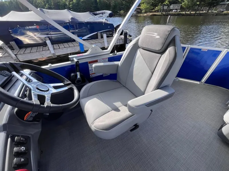 Slide: The Image of 2024 Bennington 22SVL-SPS boat interior with steering wheel and captain's chair by the lake. - 18