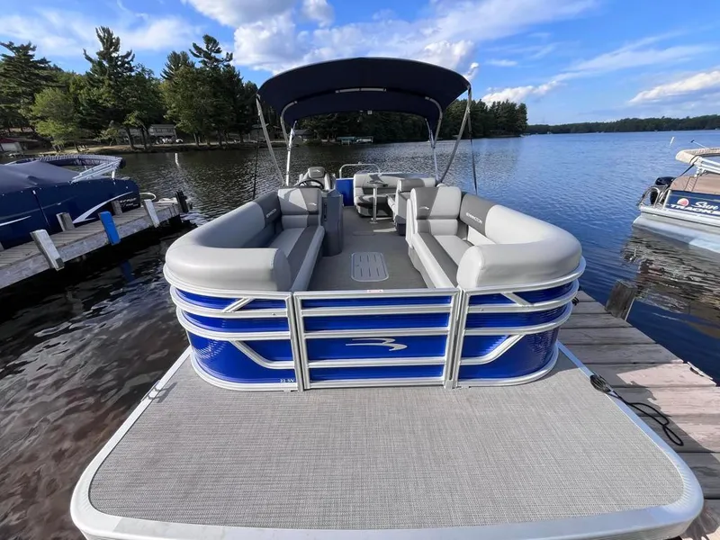 Slide: The Image of 2024 Bennington 22SVL-SPS pontoon boat docked on a serene lake. - 5