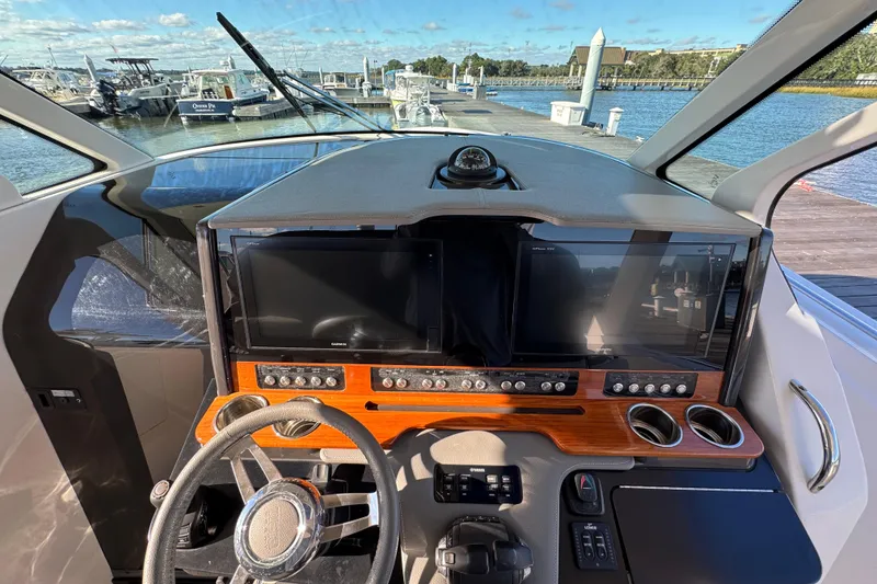 Slide: The Image of 2019 Tiara Sport 38 LS helm with dual screens and wooden dashboard at marina. - 15