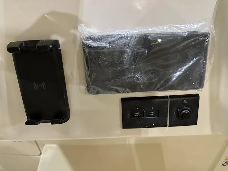 Slide: The Image of Control panel of 2024 Grady-White Express 330 boat with start/stop buttons and phone holder. - 10