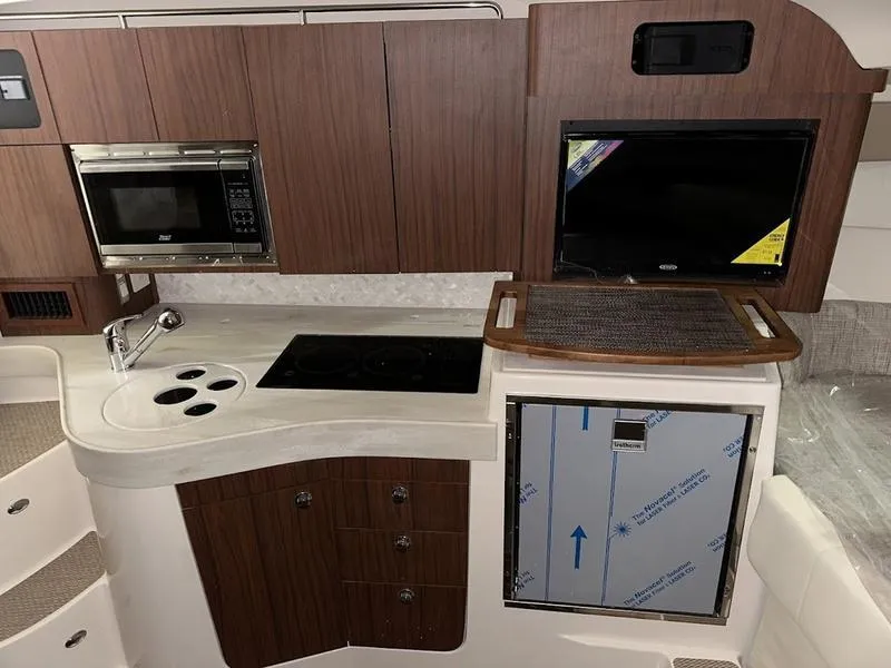 Slide: The Image of 2024 Grady-White Express 330 boat kitchen with microwave, stove, sink, and storage cabinets. - 21