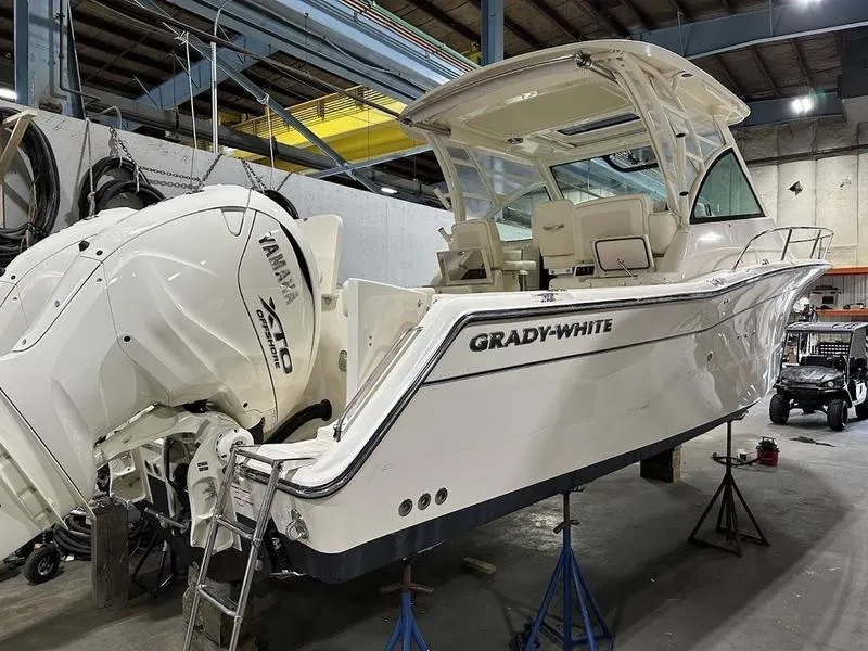 Slide: The Image of 2024 Grady-White Express 330 boat in a warehouse, featuring twin Yamaha outboard engines. - 6