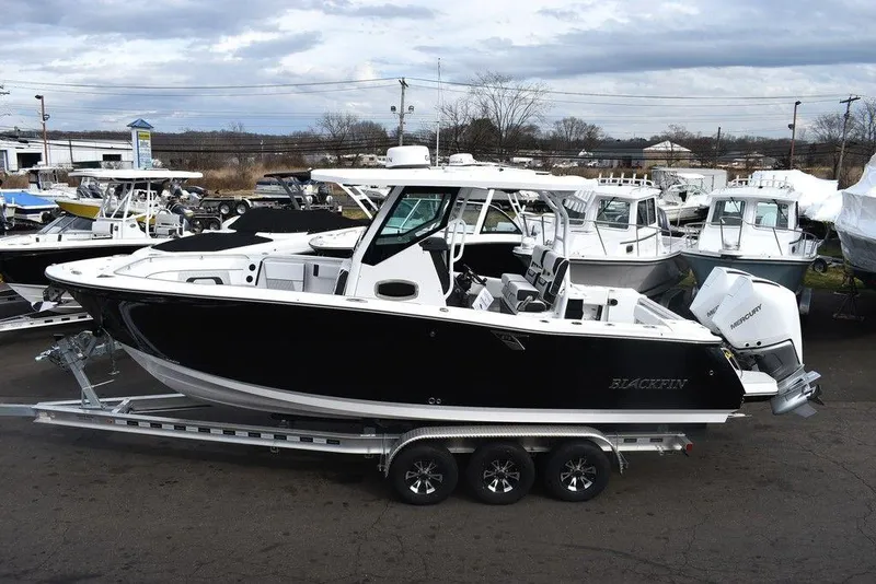 Slide: The Image of 2024 Blackfin 272CC boat on a trailer in a marina. - 2