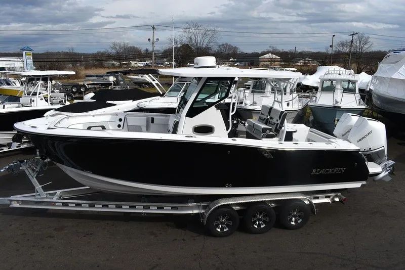 Slide: The Image of 2024 Blackfin 272CC boat on a trailer in a marina. - 3