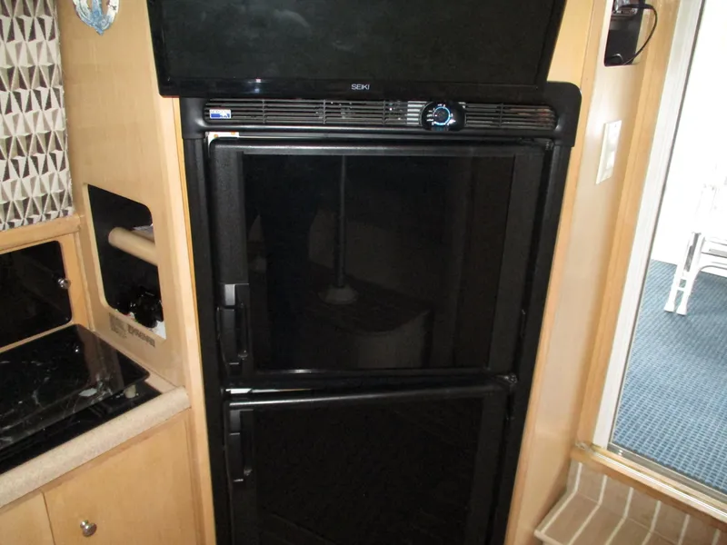 Slide: The Image of 1997 Carver Voyager interior with black refrigerator and wooden cabinetry. - 31
