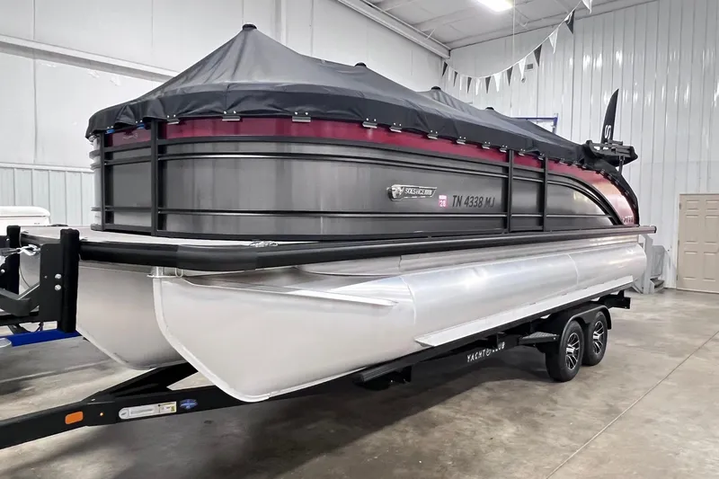 Slide: The Image of 2024 Harris Solstice 230 pontoon boat in a showroom, covered and on a trailer. - 2