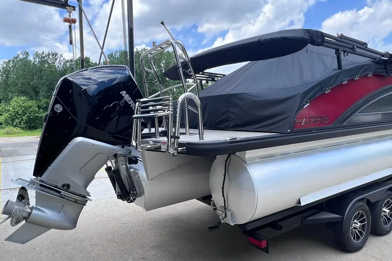 Slide: The Image of 2024 Harris Solstice 230 pontoon boat with Mercury outboard motor, parked on a trailer. - 7