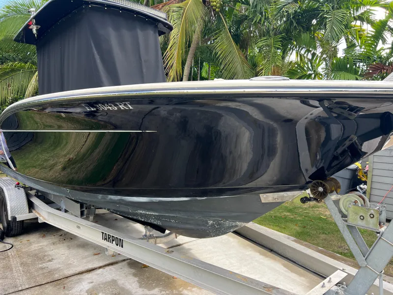 Slide: The Image of 2019 Scout 255LXF boat on a trailer, side view with lush greenery in the background. - 13