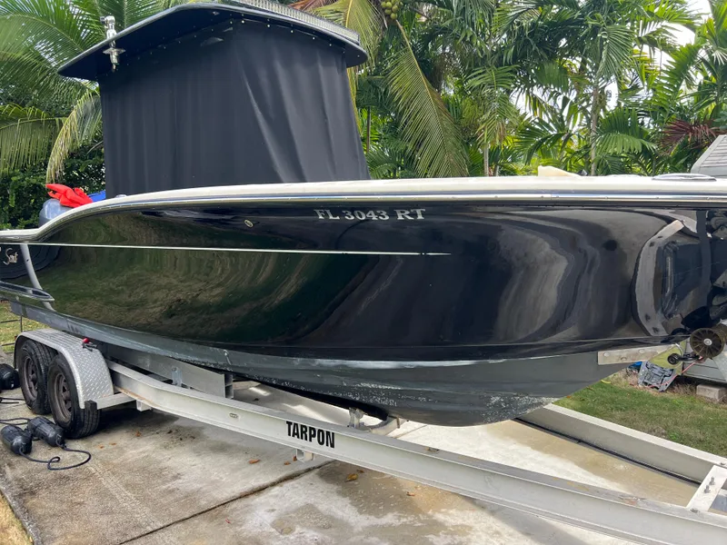 Slide: The Image of 2019 Scout 255LXF boat on a Tarpon trailer, black hull, parked outdoors. - 16
