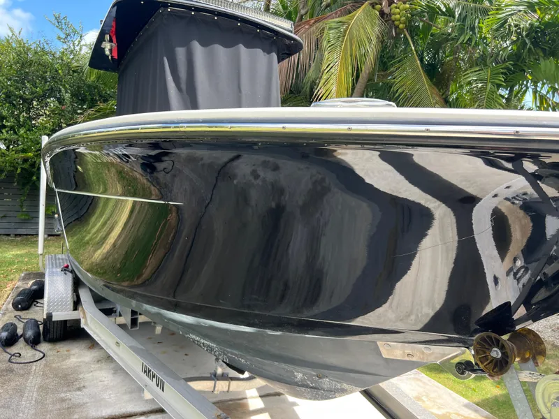 Slide: The Image of 2019 Scout 255LXF boat on trailer, black hull, palm trees in background. - 23