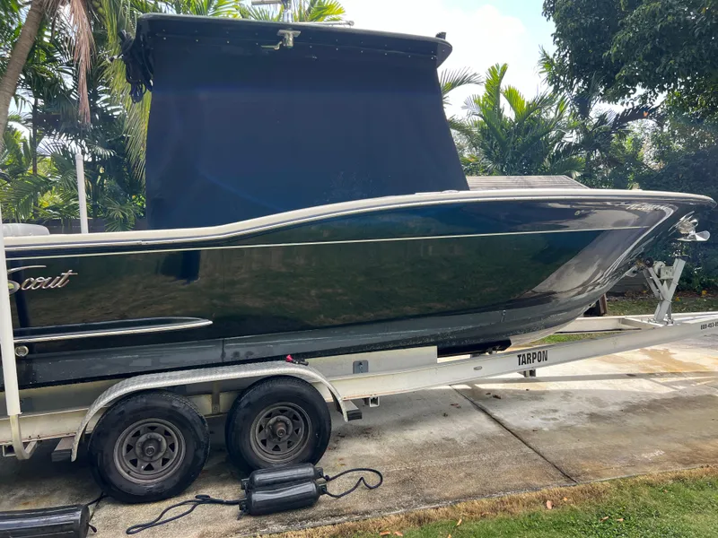 Slide: The Image of 2019 Scout 255LXF boat on a trailer, covered and parked outdoors. - 25
