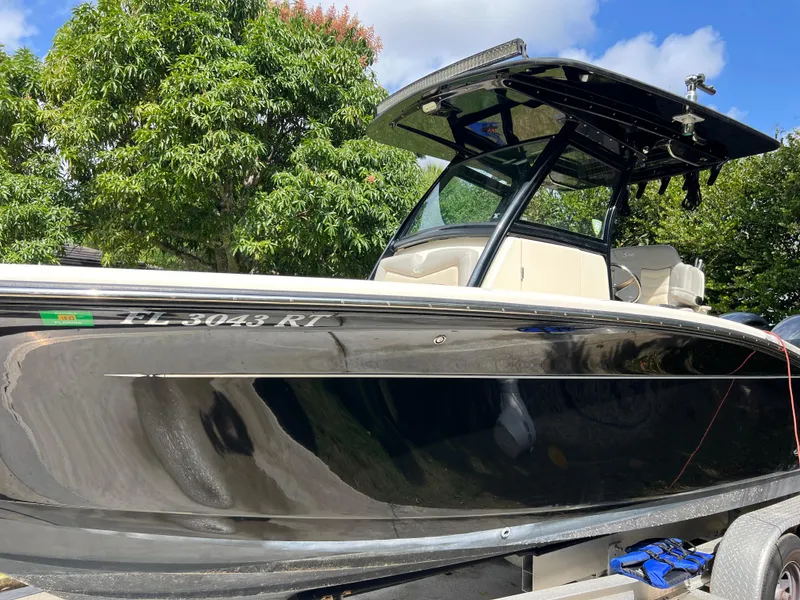 Slide: The Image of 2019 Scout 255LXF boat on trailer with black hull and T-top. - 9
