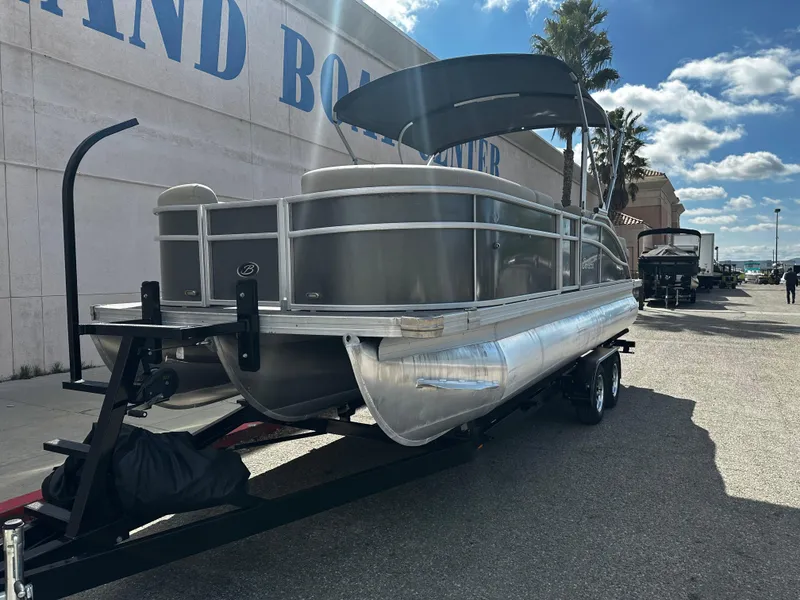 Slide: The Image of 2021 Barletta C22U pontoon boat on a trailer outside a boat center. - 10
