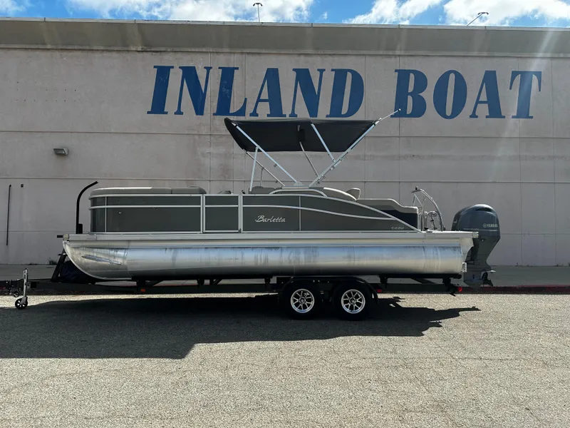 Slide: The Image of 2021 Barletta C22U pontoon boat on a trailer outside Inland Boat dealership. - 8
