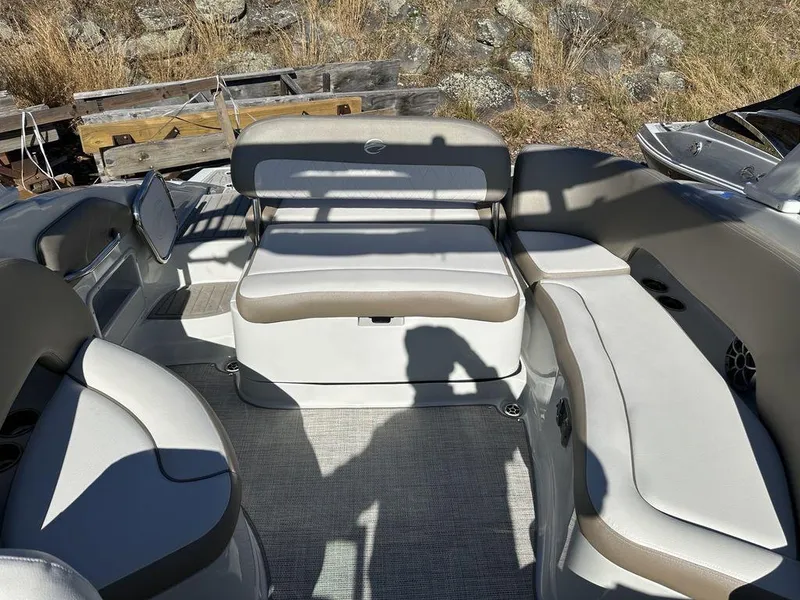 Slide: The Image of 2024 Crownline E Series E255 boat interior with cushioned seating and outdoor backdrop. - 14