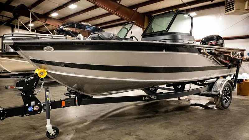 The Image of 2024 Lund 1875 Impact XS Sport boat on trailer in indoor showroom. - 0