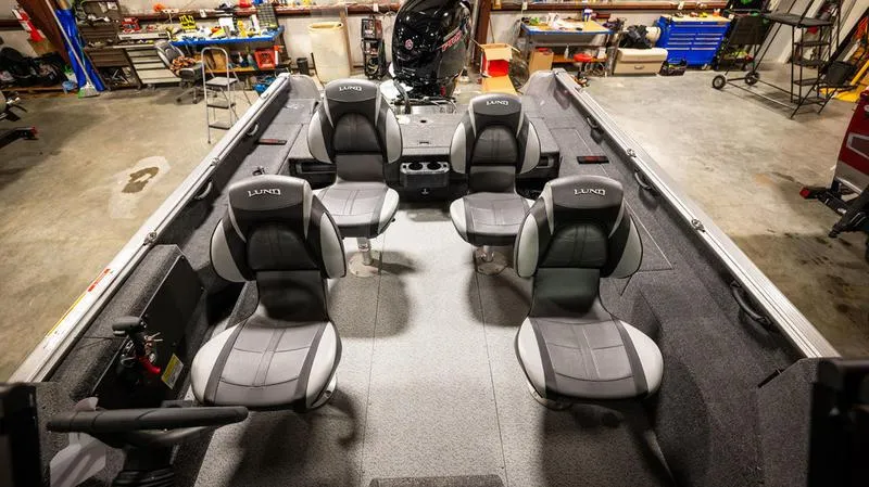 Slide: The Image of 2024 Lund 1875 Impact XS Sport boat interior with four seats in a garage. - 21
