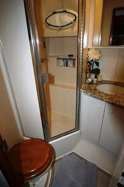 Slide: The Image of 1999 Silverton 392 Motor Yacht bathroom with shower, granite countertop, and wooden toilet seat. - 24