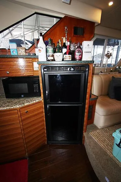 Slide: The Image of Interior of 1999 Silverton 392 Motor Yacht with fridge, microwave, and liquor bottles. - 32