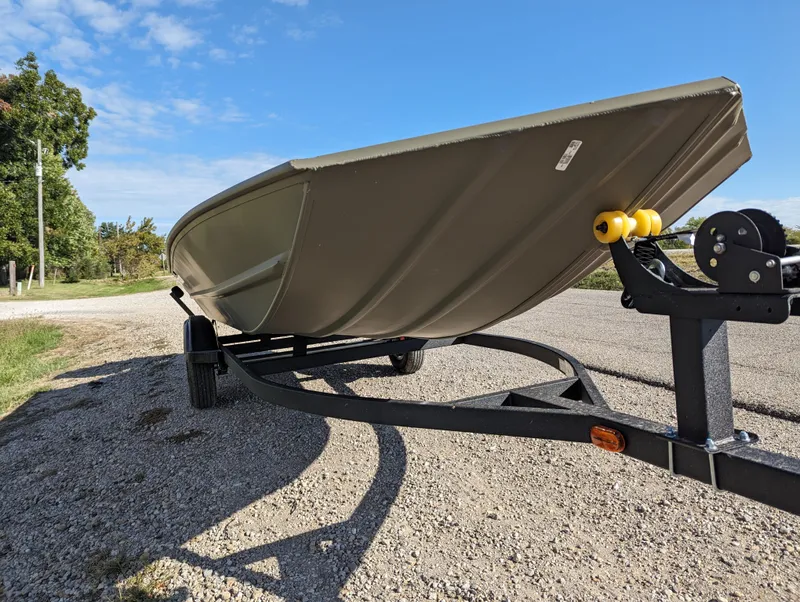 Slide: The Image of 2024 Tracker Grizzly 1754 SC boat on a trailer, parked on a gravel road. - 10