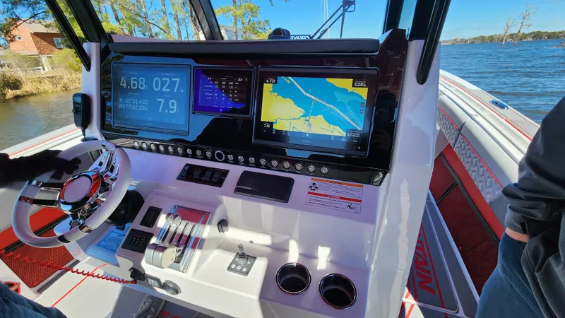 Slide: The Image of 2024 Fountain 38 SC boat dashboard with navigation screens and steering wheel. - 16