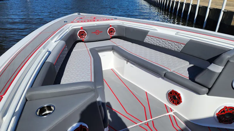 Slide: The Image of 2024 Fountain 38 SC boat interior with gray and red seating, docked by the water. - 9