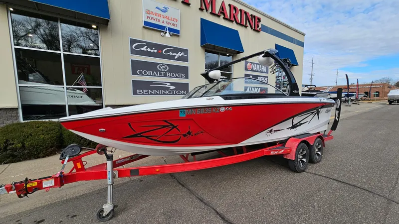 Slide: The Image of 2013 Tigé Z1 red boat on trailer outside marine dealership. - 2