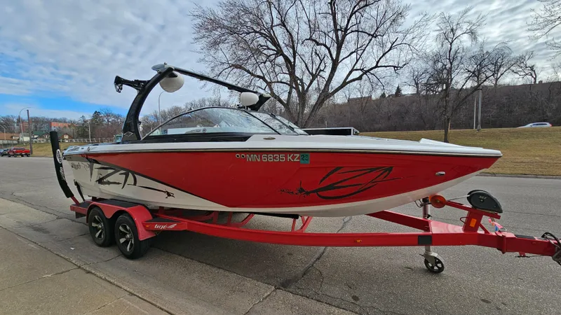Slide: The Image of 2013 Tigé Z1 boat on a red trailer, parked on a street. - 3
