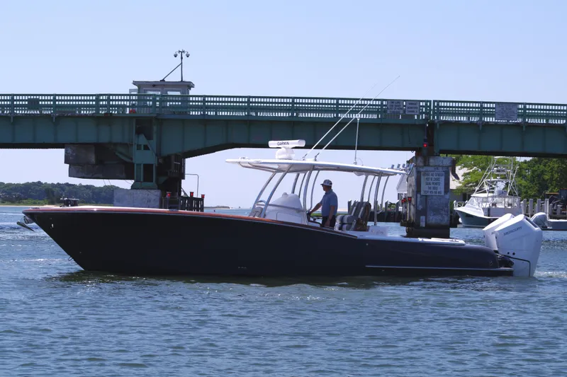 Slide: The Image of 2024 Mag Bay 33 CC boat cruising under a bridge on a sunny day. - 4