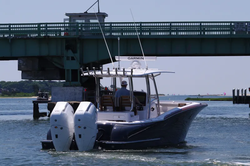 Slide: The Image of 2024 Mag Bay 33 CC boat cruising under a bridge with twin outboard engines. - 7