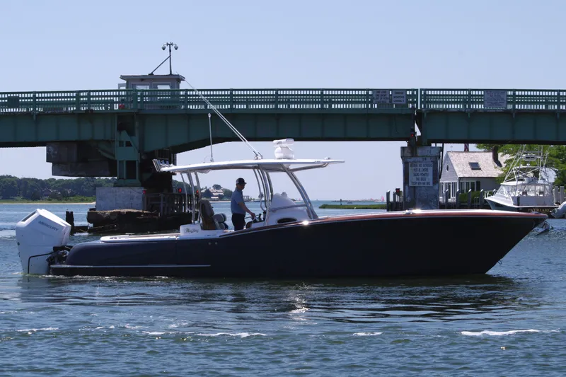 Slide: The Image of 2024 Mag Bay 33 CC boat cruising under a bridge on a sunny day. - 9