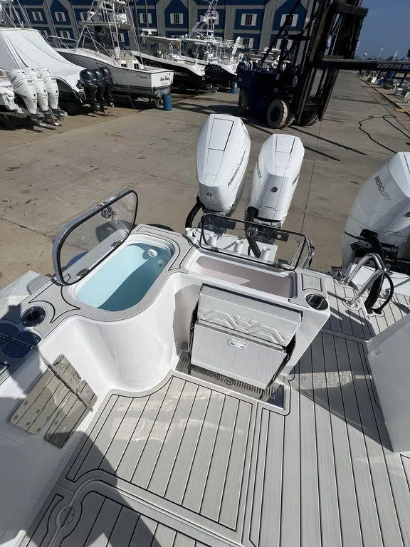 Slide: The Image of 2024 Twin Vee 400 Center Console GFX boat with dual outboard engines at a marina. - 12