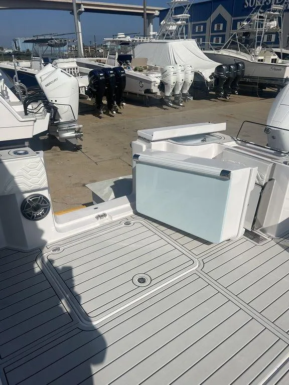 Slide: The Image of 2024 Twin Vee 400 Center Console GFX boat at a marina with multiple outboard engines. - 15