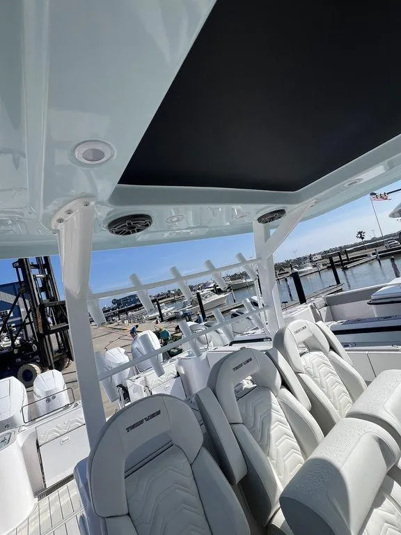 Slide: The Image of 2024 Twin Vee 400 Center Console GFX boat interior with luxurious seating at a marina. - 22