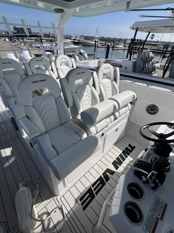 Slide: The Image of 2024 Twin Vee 400 Center Console GFX boat interior with white seating at marina. - 25