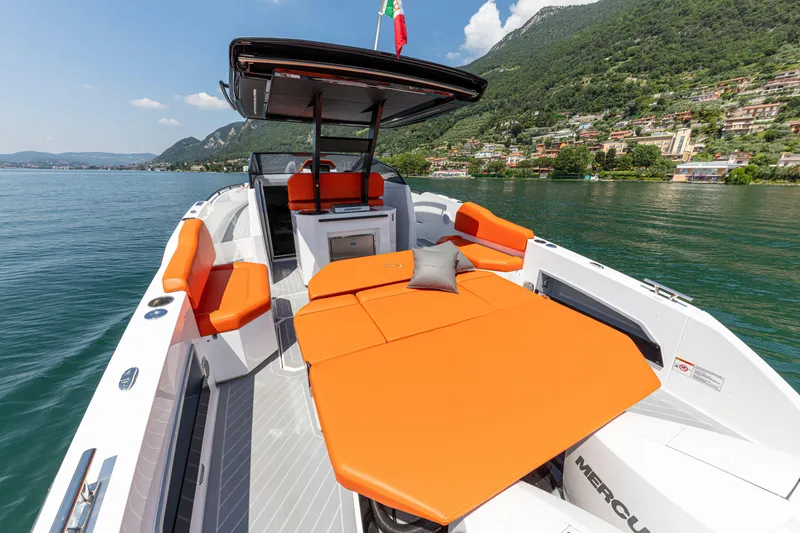 Slide: The Image of 2024 Rio Yachts Daytona 35 with vibrant orange seating, cruising on a scenic lake. - 24