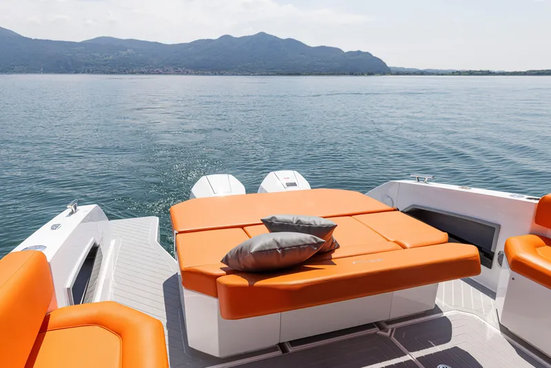 Slide: The Image of 2024 Rio Yachts Daytona 35 with orange seating, scenic lake view, and mountains in the background. - 25