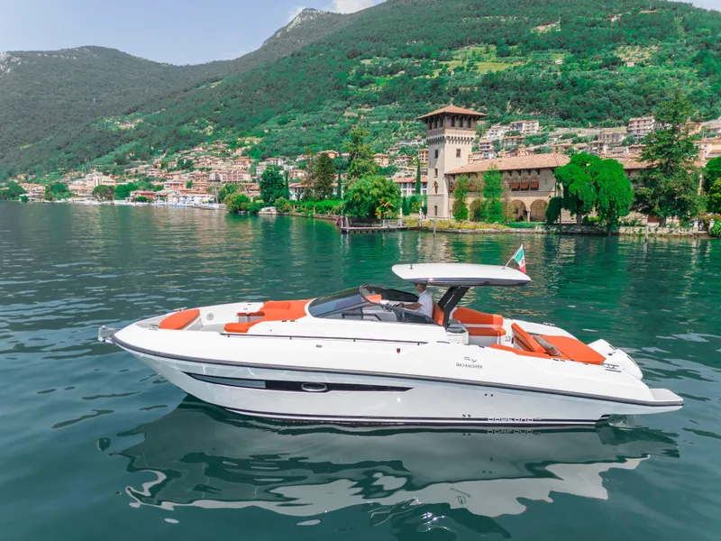 Slide: The Image of 2024 Rio Yachts Daytona 35 cruising on a scenic lake with lush green hills. - 5