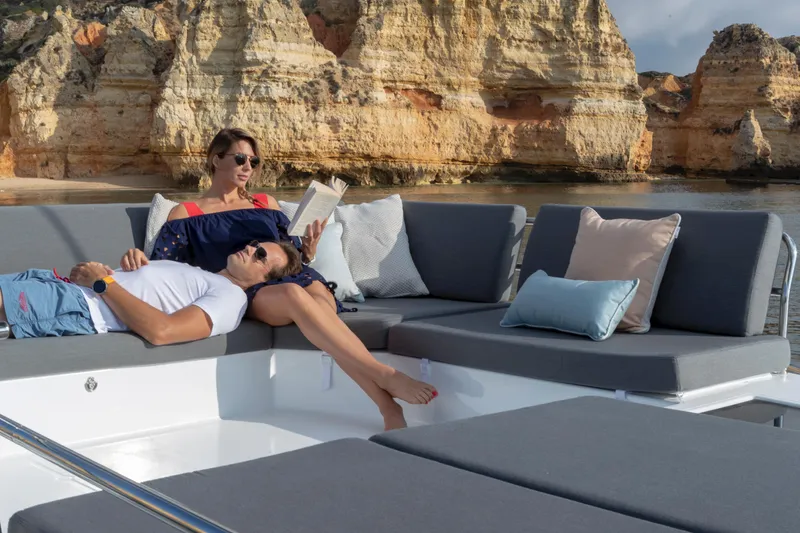 Slide: The Image of Couple relaxing on 2024 Fountaine Pajot Elba 45 catamaran with scenic cliffs in background. - 5