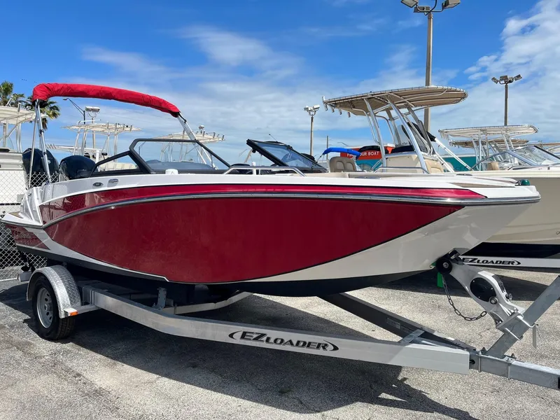 Slide: The Image of 2018 Glastron GTD boat on EZ Loader trailer, red and white, parked at marina. - 3