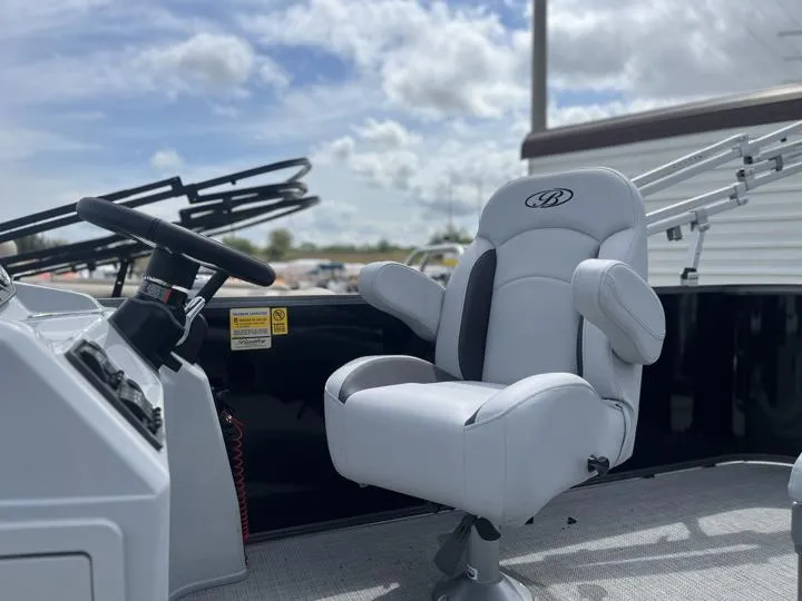 Slide: The Image of 2024 Bentley Pontoons LE 180 3 PT captain's chair and helm under a cloudy sky. - 28