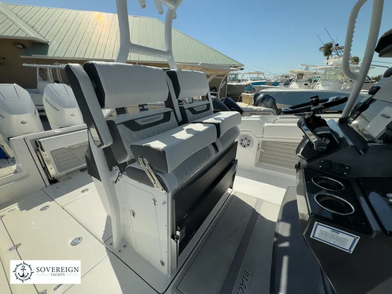 Slide: The Image of 2024 Blackfin 302CC boat interior with seating and console, docked at a marina. - 25
