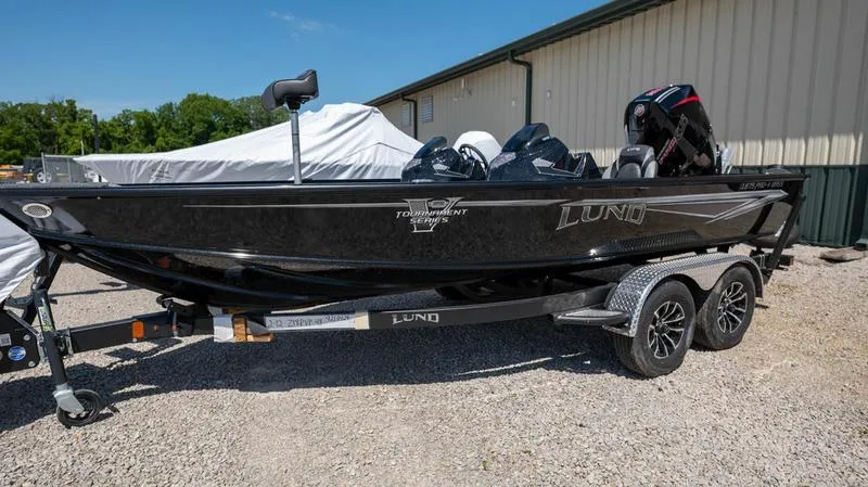 The Image of 2024 Lund 1875 Pro-V Bass XS boat on a trailer, parked outdoors. - 1