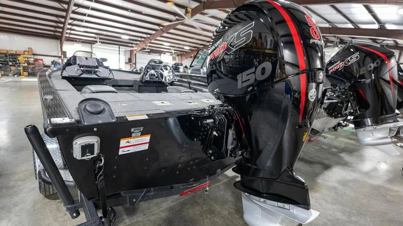 Slide: The Image of 2024 Lund 1875 Pro-V Bass XS boat with a powerful 150 HP engine in a showroom. - 10
