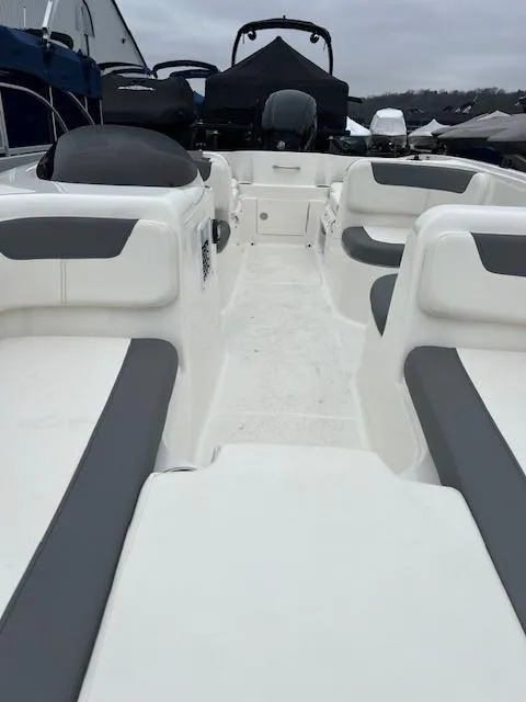 Slide: The Image of 2023 Bayliner Element E18 boat interior with gray and white seating, docked outdoors. - 10