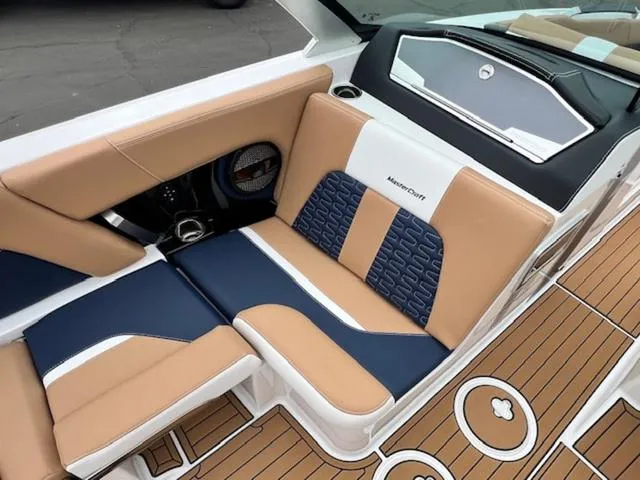 Slide: The Image of 2024 MasterCraft X24 boat interior with beige and blue seating. - 14