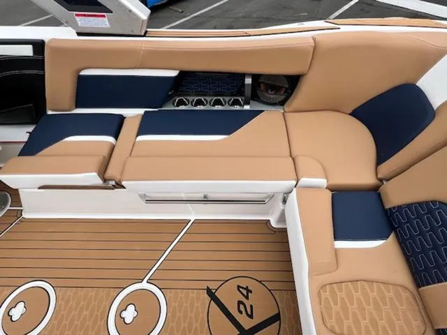Slide: The Image of 2024 MasterCraft X24 boat interior with beige and blue cushioned seating. - 18